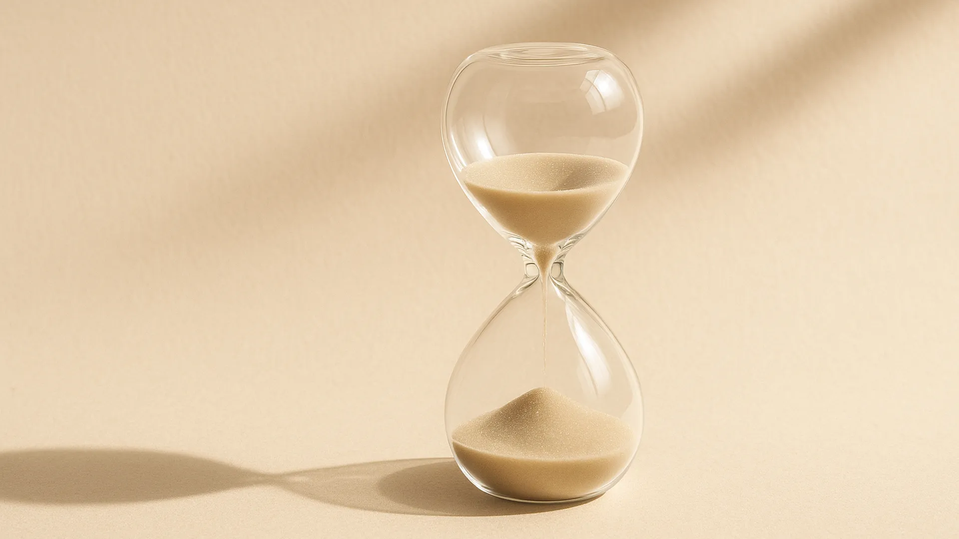 레티노이드 병행 루틴 사이의 휴식을 상징하는 투명한 유리 타이머가 부드러운 자연광 아래 놓인 미니멀 이미지